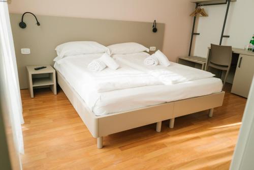 a bedroom with a bed with white sheets and pillows at Ventus Park Hotel in Nago-Torbole
