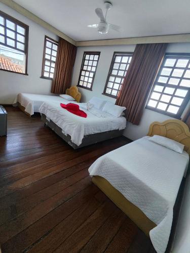 two beds in a room with wooden floors and windows at POUSADA FLOR DE LIS in Diamantina