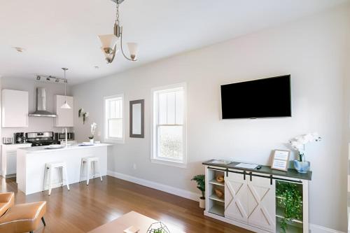 a kitchen and living room with white walls and a flat screen tv at Jennifer's Walkable Private Apartment Getaway with Relaxing Deck in Providence