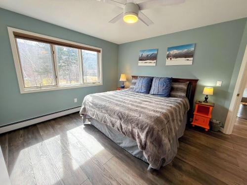 a bedroom with a bed with blue walls and two windows at F32 Modern Golf Course Home with Mountain Views in Bretton Woods