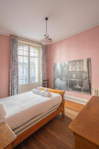 - une chambre avec des murs roses, un lit et une fenêtre dans l'établissement Chaperonnière, à Angers