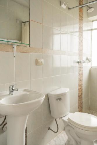 a white bathroom with a toilet and a sink at Sueños del Valle Sagrado in Urubamba