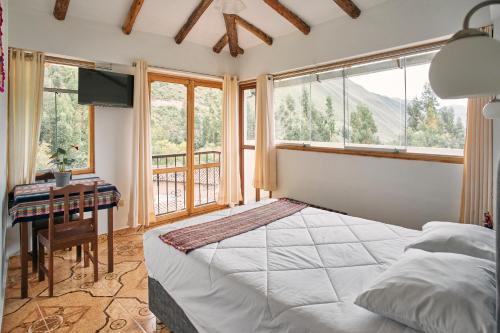 a bedroom with a bed and a desk and windows at Sueños del Valle Sagrado in Urubamba