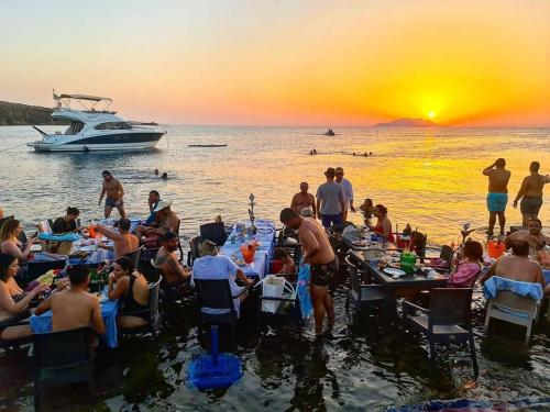 a group of people sitting in the water watching the sunset at Studio Yakina in El Haouaria