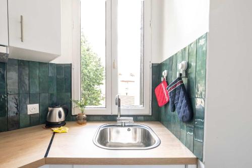 une cuisine avec un évier et une fenêtre dans l'établissement Le Dupont - Métro 13, 20 min Champs-Elysées, à Asnières-sur-Seine