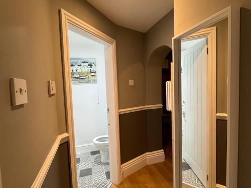 a bathroom with a toilet and a door to a room at Hargate Hall Self Catering in Buxton