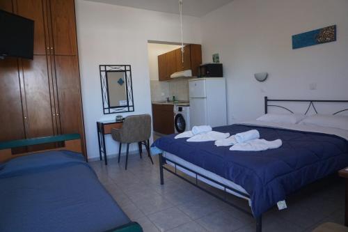 a bedroom with a bed and a desk and a kitchen at Nicholas Waves Beach Studios in Lardos