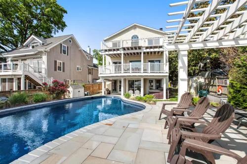 a swimming pool with chairs and a house at Oasis by the Bay - Waterfront Heated Pool Hot Tub in Annapolis
