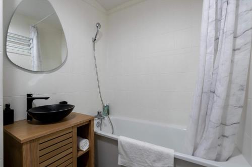 une salle de bain avec un lavabo, un miroir et une baignoire dans l'établissement Studio JadOr gare RER B Le Bourget - Paris aeroport Charles de Gaulle, au Bourget