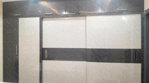 a glass shower door with black and white tile at Vizag Venya Vihar a 2BHK Deluxe Furnished HomeStays in Visakhapatnam