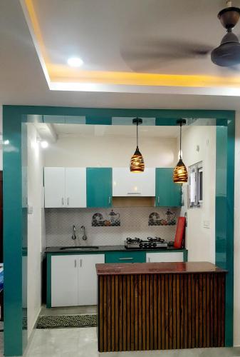 a kitchen with green and white cabinets and a counter at Vizag Venya Vihar a 2BHK Deluxe Furnished HomeStays in Visakhapatnam