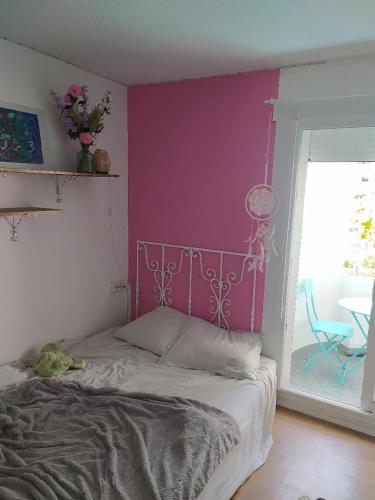 une chambre avec un lit avec un mur rose dans l'établissement Appartement Le Bouscat, à Le Bouscat