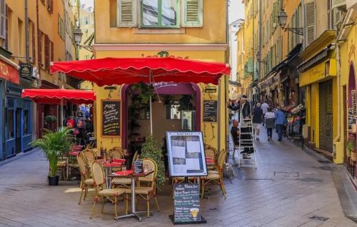 an outdoor cafe with tables and chairs and a red umbrella at Central Super Loft in Nice