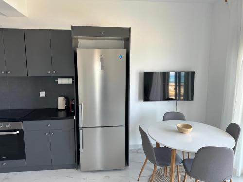 a kitchen with a white table and a stainless steel refrigerator at Villa Thea in Káto Ássos