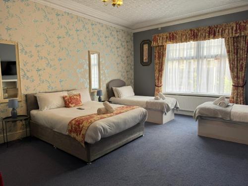 a bedroom with two beds and a couch and a window at The Calder House Hotel in Seascale