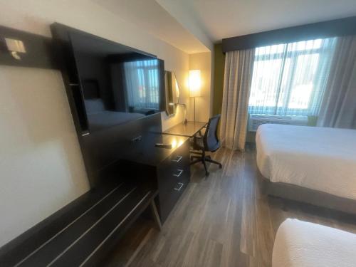a hotel room with a bed and a desk with a mirror at Holiday Inn Express Long Island City E - New York by IHG in Queens