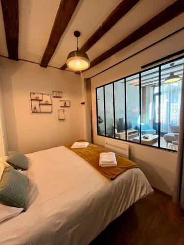 une chambre avec un grand lit et une grande fenêtre dans l'établissement La Porte Chartraine - Appartement avec terrasse au coeur de Blois, à Blois