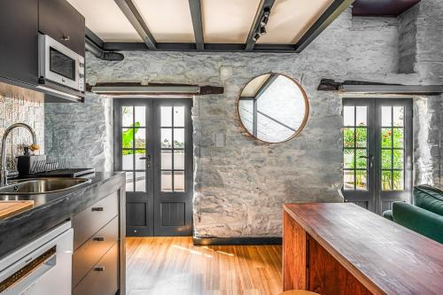 a kitchen with a stone wall and a mirror at NEW! Nature Paradise with Ocean View & Hot Tubs in Fajã da Ovelha