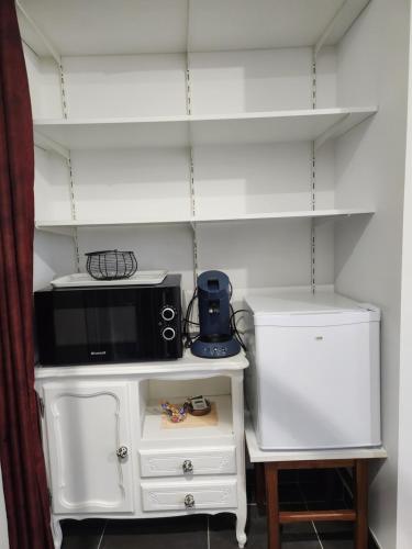 Un four micro-ondes est installé au-dessus d'une armoire blanche. dans l'établissement Chambre Cosy, à Juillan