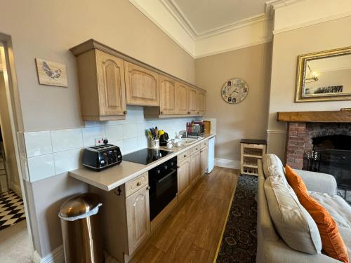 a kitchen with wooden cabinets and a stove at Hargate Hall Self Catering in Buxton
