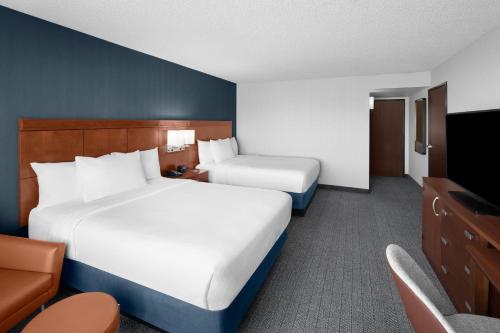 a hotel room with two beds and a flat screen tv at Courtyard by Marriott Salt Lake City Sandy in Sandy