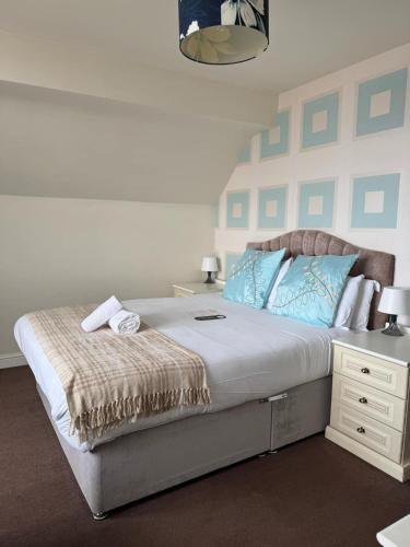 a bedroom with a large bed with blue pillows at The Calder House Hotel in Seascale