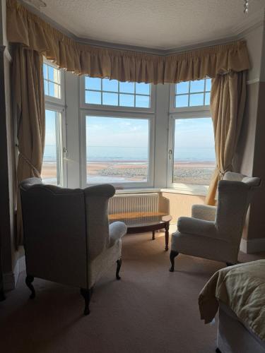 a living room with two chairs and a large window at The Calder House Hotel in Seascale