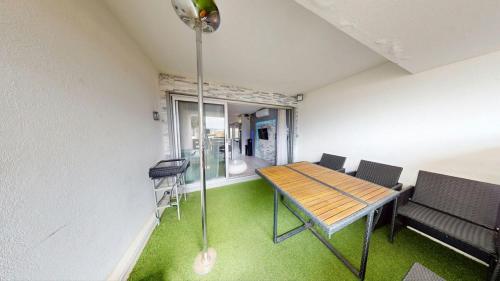 Cette chambre dispose d'une table, de chaises et d'une moquette verte. dans l'établissement Le Cocon Port Nature 5 Village Naturiste Cap d'Agde, au Cap d'Agde