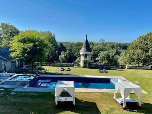 - une piscine dans une cour avec 2 chaises et une église dans l'établissement Gîtes charmants en Berry avec piscine et spa - FR-1-591-729, à Saint-Cyran-du-Jambot