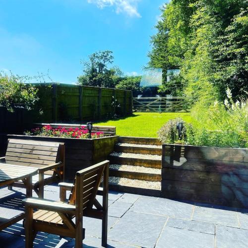 a patio with a table and a bench and flowers at Luxury Three Bedroom Barn Conversion in Devon in Hemyock