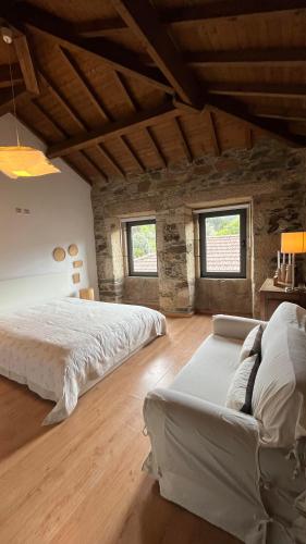 a large bedroom with a large bed and a couch at Casa do Páteo in Macieira de Alcoba