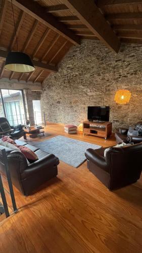 a living room with leather furniture and a stone wall at Casa do Páteo in Macieira de Alcoba