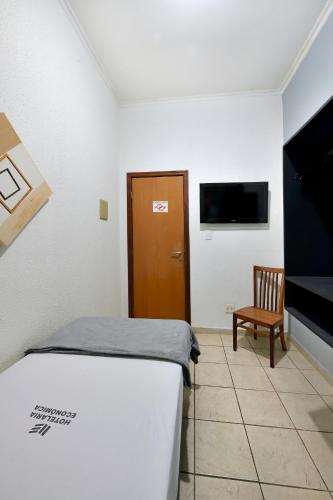 a room with two beds and a tv and a chair at Ribeirão Plaza Hotel in Ribeirão Preto