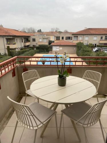 a white table and chairs on a balcony at Aux Cyprès du littoral T 2 avec piscine in Poussan