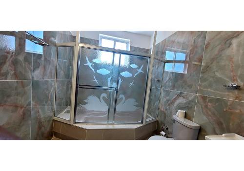 a shower with glass doors in a bathroom with a toilet at Belo Residence in Cap-Haïtien