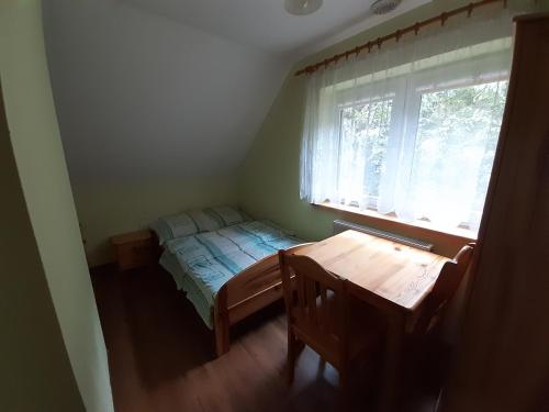 a bedroom with a bed and a table and a window at Domek Pod Jawornikiem in Wetlina
