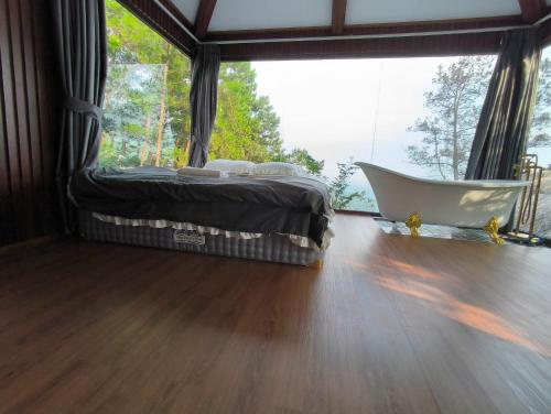 a bedroom with a bed and a tub in front of a window at Mimosa 226 - phòng săn mây in Tam Ðảo