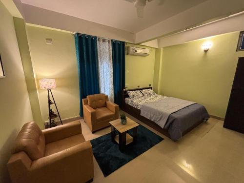 a bedroom with a bed and a couch and a chair at Placid Homestay in Guwahati