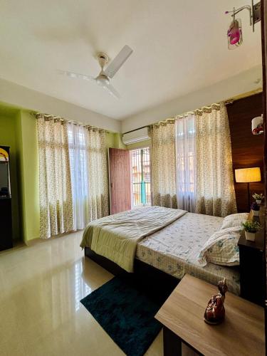a bedroom with a bed and a table and windows at Placid Homestay in Guwahati