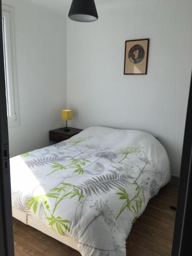 - un lit avec une couette blanche et des plantes dans l'établissement Petit bijoux, à La Tremblade