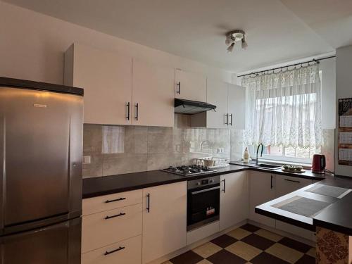 a kitchen with white cabinets and a stainless steel refrigerator at Apartament Krola Stefana Batorego in Kielce