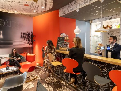 a group of people sitting at a bar in a restaurant at ibis Le Puy-en-Velay Centre in Le Puy en Velay