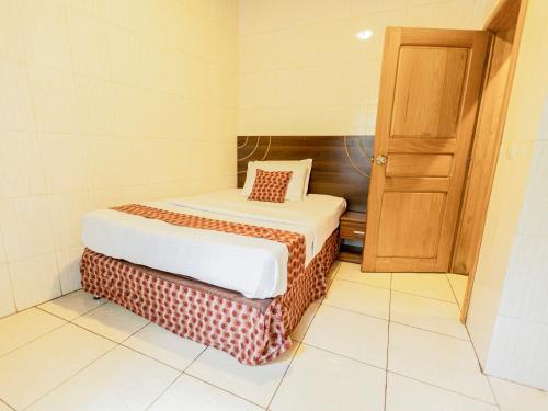 a small room with a bed and a wooden door at Hotel Saint jean Leopold Apartment in Kigali