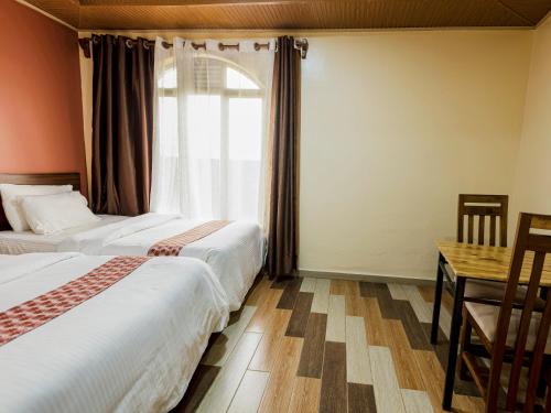 two beds in a room with a table and a window at Hotel Saint jean Leopold Apartment in Kigali