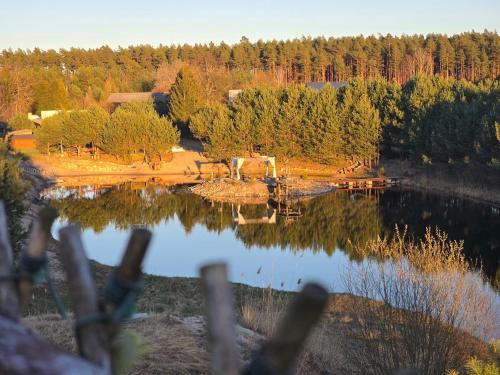 a view of a lake through a fence at Domki Bory Tucholskie - Kurs na wypoczynek in Osieczna