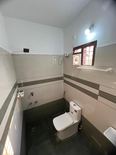 a bathroom with a toilet and a sink and a window at Enrich Tourist Homes in Agali