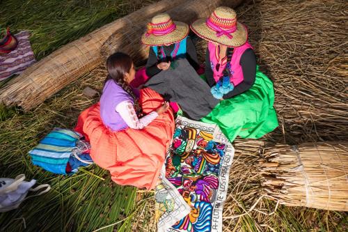a group of three girls sitting on the grass at Titicaca EcoLux in Puno
