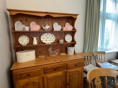 a wooden hutch with plates and dishes on it at Hargate Hall Self Catering in Buxton