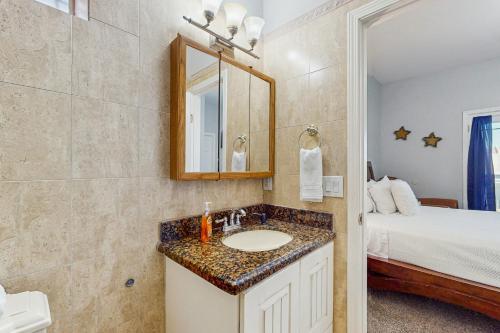a bathroom with a sink and a mirror and a bed at Pura Vida Unit A in South Padre Island