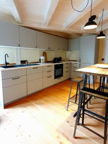 a kitchen with white cabinets and a wooden table at Stadtvilla An der Viergelindenbrücke in Rostock